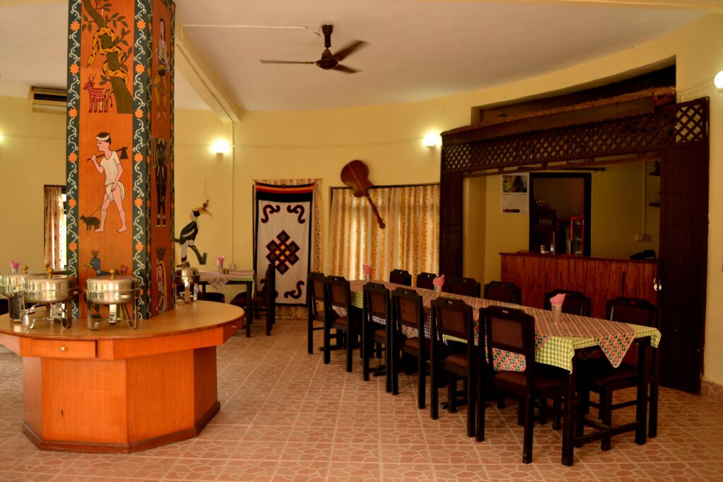 Spacious restaurant dining hall with authentic Tharu cultural wall paintings, buffet station, and wooden furniture at Rhino Lodge & Hotel Sauraha Chitwan Nepal
