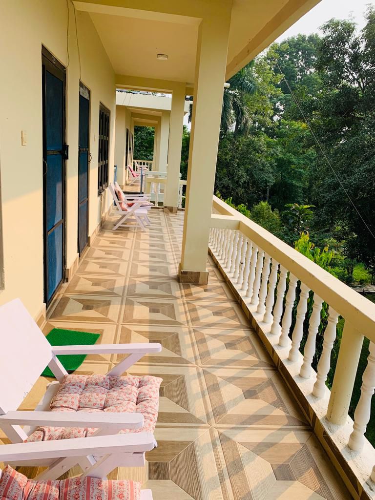 Balcony corridor with seating area at Rhino Lodge and Hotel, Sauraha, Chitwan, Nepal, overlooking lush greenery.